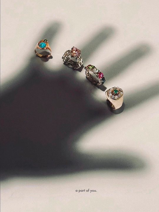 Cuatro anillos suspendidos en el aire sobre la sombra de una mano: el producto está, la persona no.